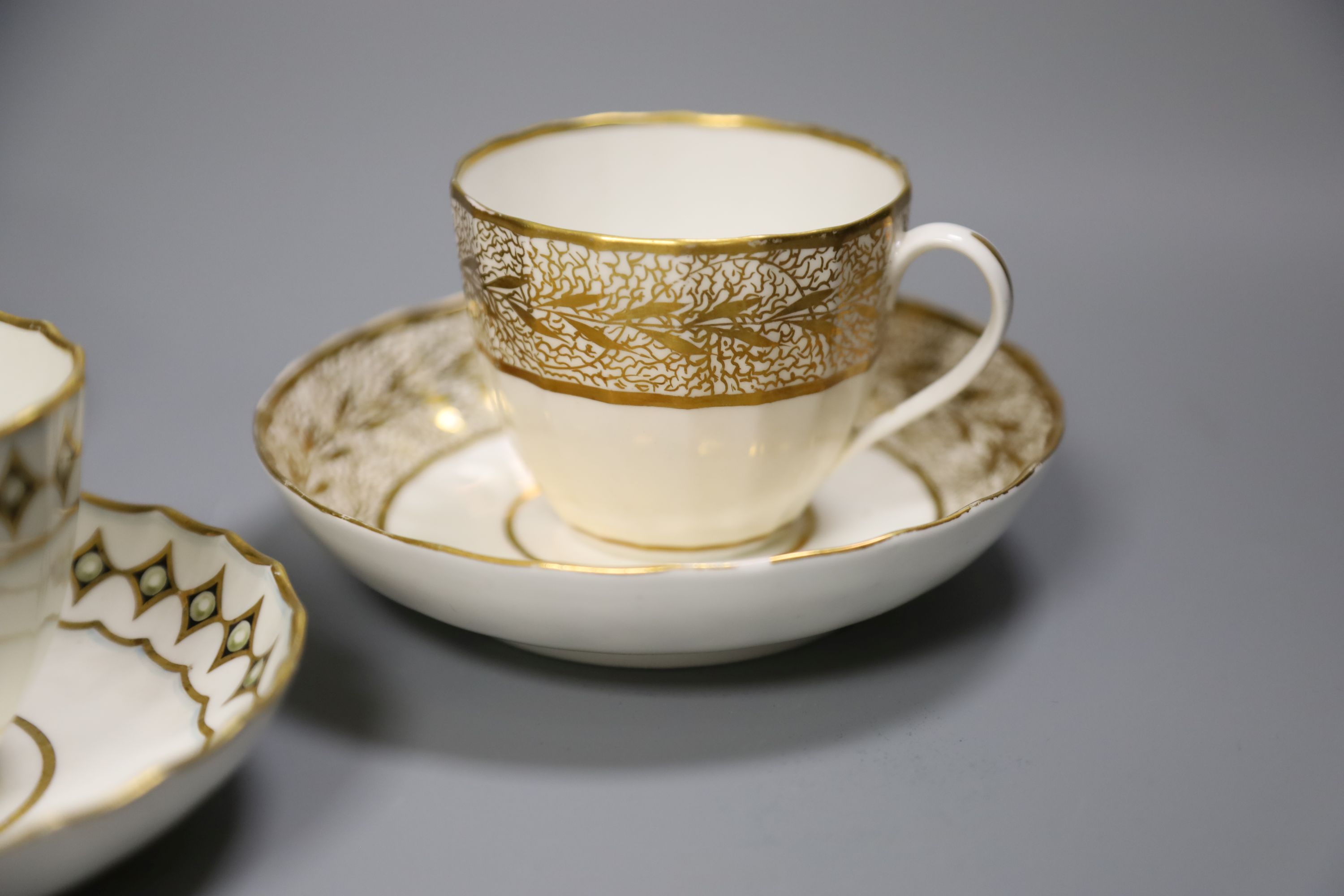 A Derby faceted teacup and saucer painted with pearls on diamond gilding pattern 135 in puce, another similar shaped Derby teacup